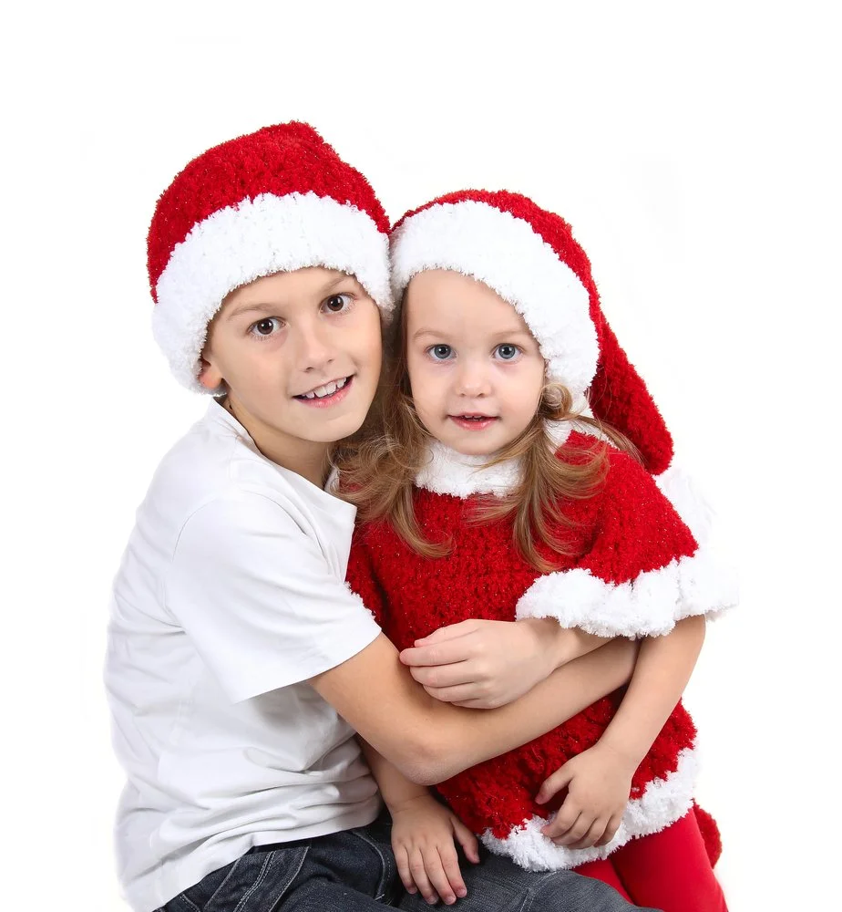 Two children in Santa hats smiling together.